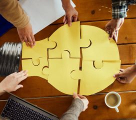 Above view of unrecognizable creative team cooperation while making light bubble of puzzles at casual office.