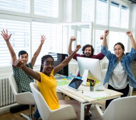 Portrait of business executives raising arms in office